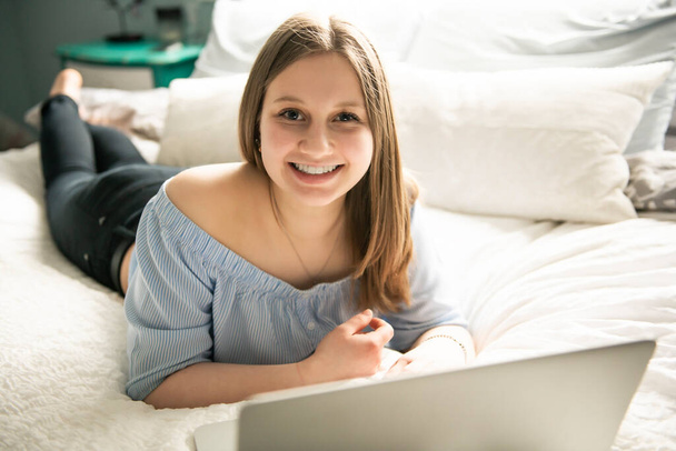 A Young smiling teen girl on bed with laptop - Foto, Imagen