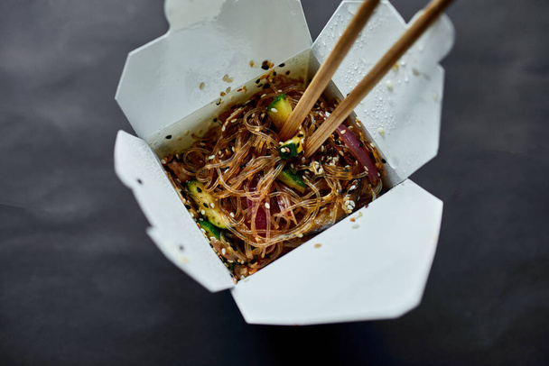 Tasty Udon noodles pasta with tempuru, shrimps wok in box delivery and wooden sticks, Japanese spicy food, Box with Thai food, concept of fast food delivery. - Photo, Image