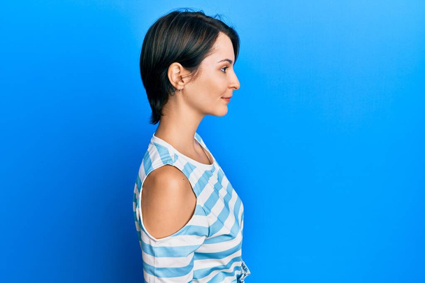 Young brunette woman with short hair wearing casual striped t-shirt looking to side, relax profile pose with natural face with confident smile.  - Φωτογραφία, εικόνα