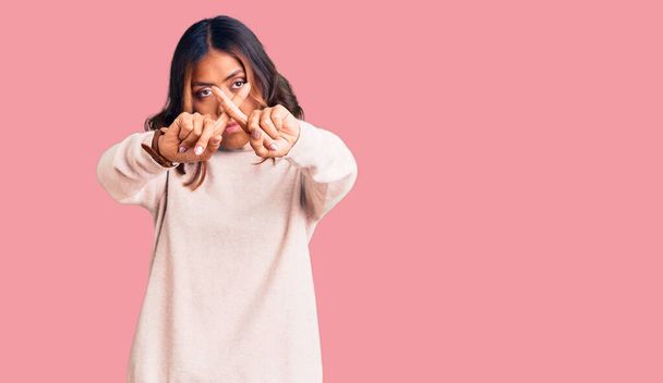 Young beautiful mixed race woman wearing winter turtleneck sweater rejection expression crossing fingers doing negative sign  - Photo, Image