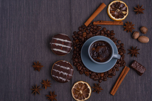 A cup of espresso is decorated with anise stars, cinnamon, sweets, dried lemons, acorns, peanuts in a beautiful dish. - Photo, Image