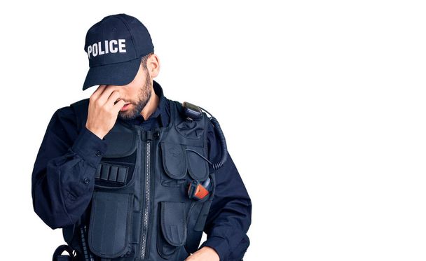 Mladý pohledný muž s plnovousem v policejní uniformě unaveně mnul nos a oči cítil únavu a bolest hlavy. koncepce stresu a frustrace.  - Fotografie, Obrázek