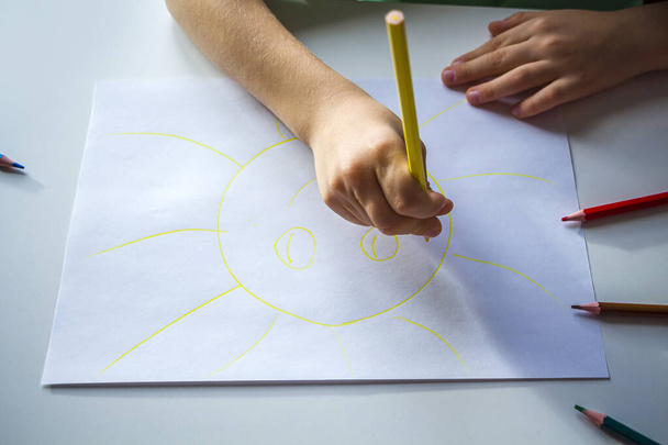 Kid draws sun with pencils. Child's creativity and art. Preschooler gets drawing skills in kindergarten. Children Protection Day - Fotó, kép