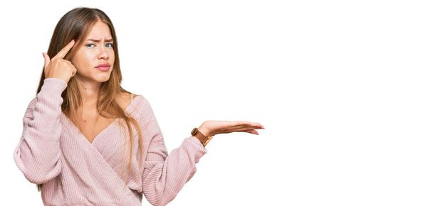 Bella donna bionda che indossa casual inverno maglione rosa confuso e infastidito con palmo aperto mostrando spazio copia e indicando dito sulla fronte. Pensaci..  - Foto, immagini