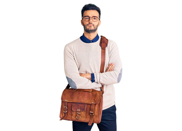 Young handsome hispanic man wearing leather bag skeptic and nervous, disapproving expression on face with crossed arms. negative person.  - Fotoğraf, Görsel