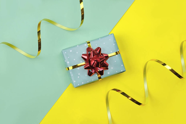 Ajándék doboz egy íj egy fényes háttér. Karácsonyi kompozíció egy ajándék csomagolva papír, kötél és egy íj. új év téma ajándék és arany szalag - Fotó, kép