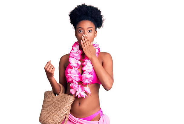 Giovane donna afroamericana in bikini e lei hawaiana che copre la bocca con la mano, scioccata e spaventata per errore. espressione sorpresa  - Foto, immagini