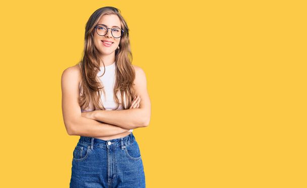 Beautiful caucasian young woman wearing casual clothes and glasses happy face smiling with crossed arms looking at the camera. positive person.  - Photo, Image