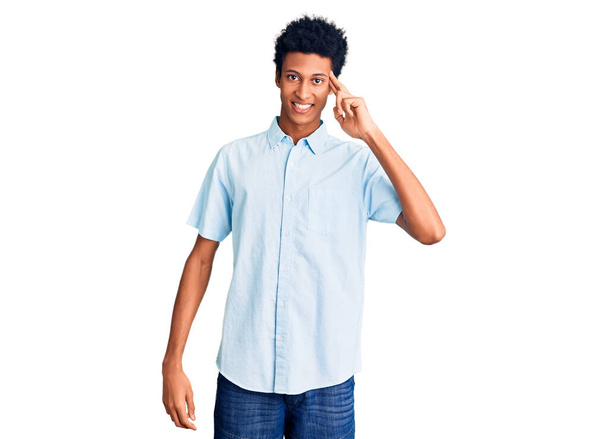 Jonge Afro-Amerikaanse man draagt casual kleding lachend wijzend naar het hoofd met één vinger, geweldig idee of gedachte, goed geheugen  - Foto, afbeelding