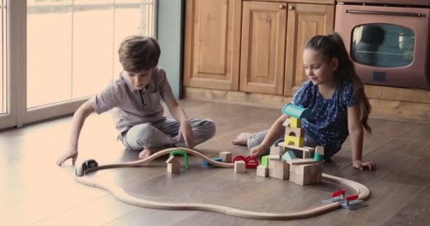 Girl and boy play toy railroad at home - 映像、動画