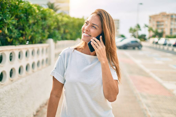 Красива середнього віку йогоіспанка посміхається говорити по телефону щасливий на відкритому повітрі
 - Фото, зображення