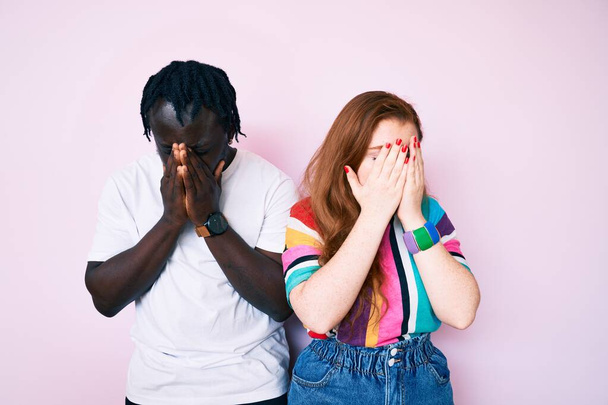 Interracial couple wearing casual clothes with sad expression covering face with hands while crying. depression concept.  - Foto, Imagem