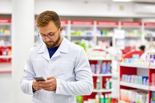 handsome pharmacist man using smartphone at work - Foto, Imagem