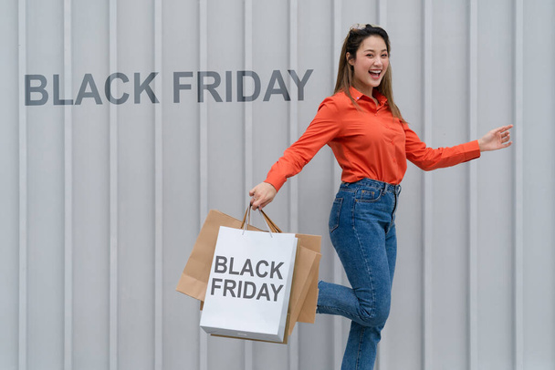 Black Friday concept, Woman holding many shopping bags walking with colorful shopping bags near the store during shopping process - Photo, Image