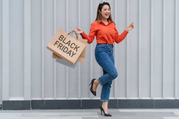 Black Friday concept, Woman holding many shopping bags walking with colorful shopping bags near the store during shopping process - 写真・画像