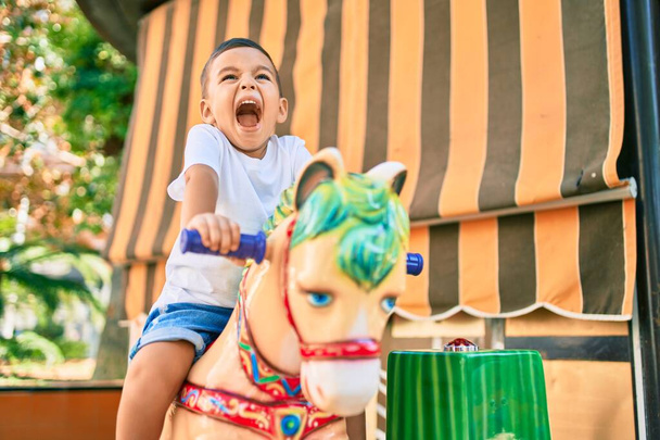 Αξιολάτρευτο ισπανόφωνο αγόρι χαμογελάει χαρούμενο παίζοντας στο πάρκο. - Φωτογραφία, εικόνα