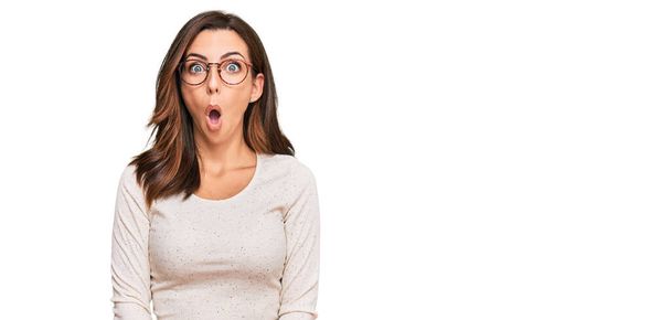 Young brunette woman wearing casual clothes and glasses afraid and shocked with surprise expression, fear and excited face.  - Photo, Image