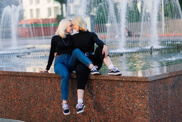 Two young females walking smiling embracing and kissing outdoor - Photo, Image