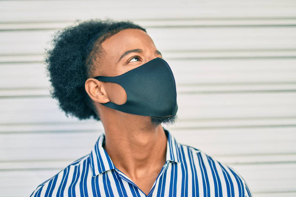 Giovane uomo afroamericano indossando maschera di protezione coronavirus passeggiando in città. - Foto, immagini