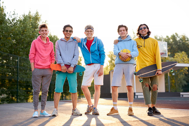 portrait of friendly team of sportive teenagers holding basketball ball and skateboard - Foto, imagen