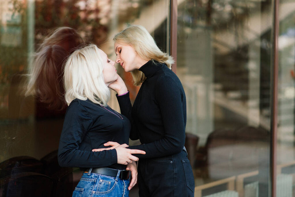 Two young females walking smiling embracing and kissing outdoor - Фото, зображення