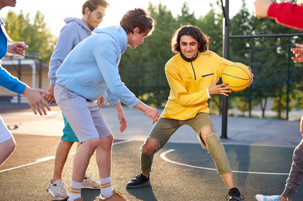 teens boys playing basketball on outdoor court, playground and having fun - Fotó, kép