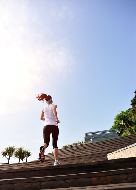 Mulher correndo em escadas de pedra à beira-mar
 - Foto, Imagem