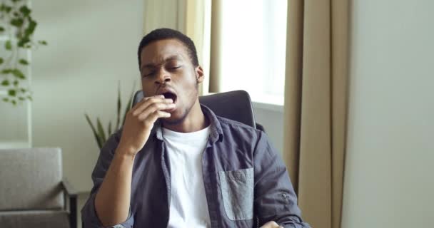 Portré afro-amerikai fickó alkalmi ruhákban ül az asztalnál otthon, vagy az irodában unatkozik. Fáradt ember ásít kinyitja a száját eltakarja a kezét szenved álmatlanság energia szüksége kávé - Felvétel, videó