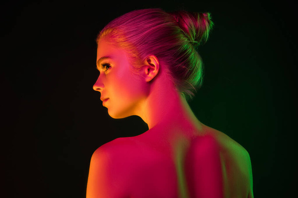 Portrait of female fashion model in neon light on dark studio background. - Photo, Image