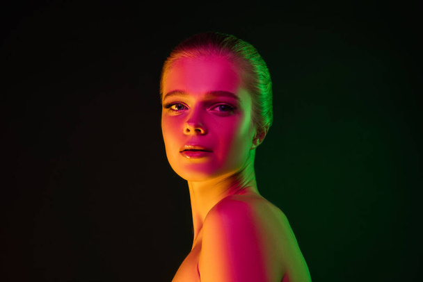 Portrait of female fashion model in neon light on dark studio background. - Foto, Imagem