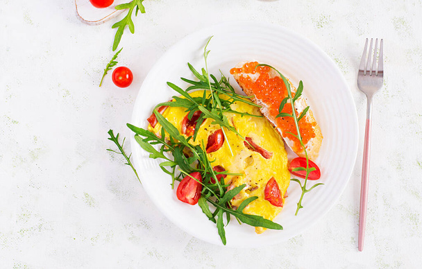 Omeleta s rajčaty, sýrem, šunkou a sendvičovým červeným kavierem na talíři. Frittata - italská omeleta. Pohled shora, režie, kopírovací prostor - Fotografie, Obrázek