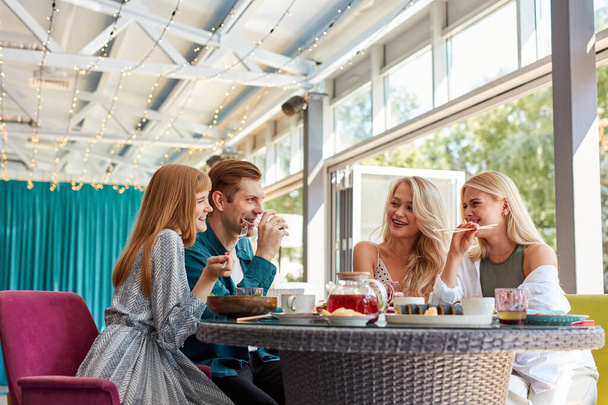 cheerful caucasian friends spending time together in bright cozy time cafe - Photo, Image