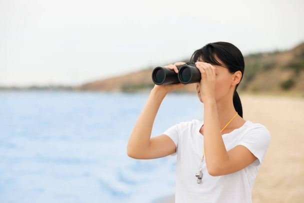 Beautiful female lifeguard with binocular near sea - Zdjęcie, obraz