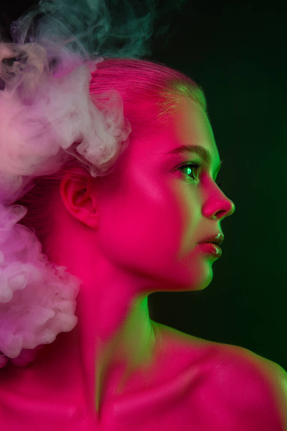 Portrait of female fashion model in neon light on dark studio background. - Foto, afbeelding