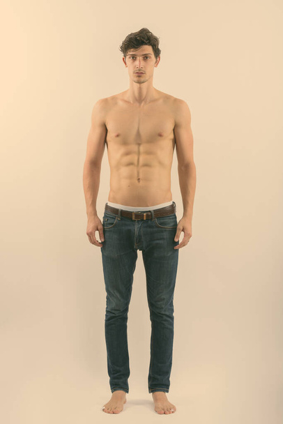 Full body shot of young handsome man standing shirtless - Фото, изображение