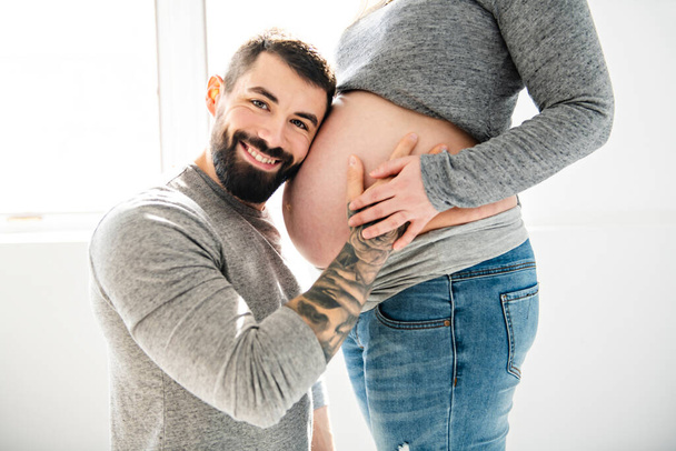 Piękna kobieta w ciąży i jej przystojny mąż z bliska spojrzeć na brzuch - Zdjęcie, obraz