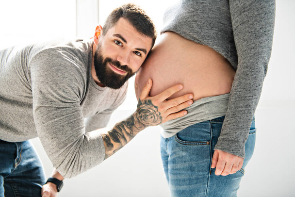 A Beautiful pregnant woman and her handsome husband close look t the belly - Foto, imagen