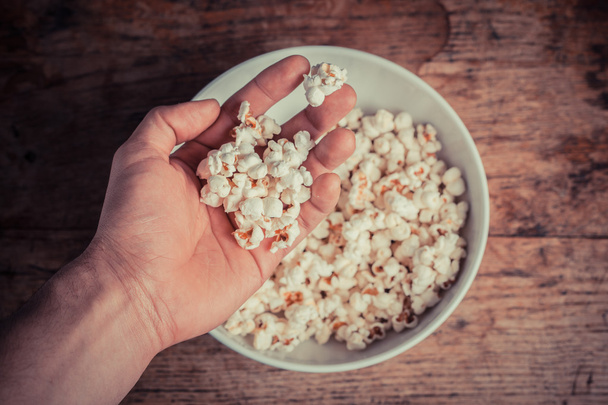 Hand getting popcorn from bowl - Фото, изображение