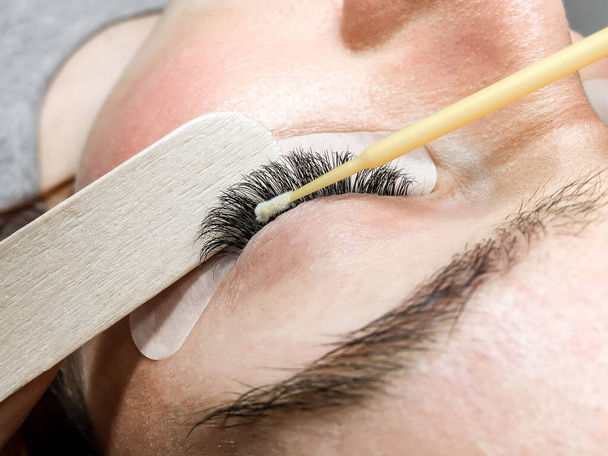 Close-up of the eyelash extension removal procedure. Portrait of a woman in a beauty salon - Foto, afbeelding