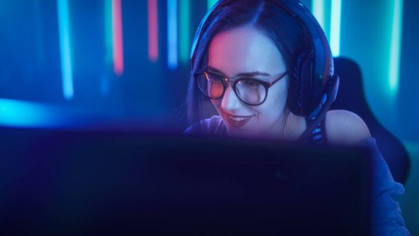 Beautiful Friendly Pro Gamer Girl Does Video Game Gameplay stream, Wearing Headset Talks Chats with Her Fans and Team into Headphones Microphone.Teenagers Having Fun. Background Cool Neon Retro - Foto, Imagen