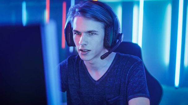 Young Pro Gamer Playing in Online Video Game, talks with Team Players through Microphone. Neon Colored Room. e-Sport Cyber Games Internet Championship. - Foto, imagen