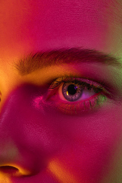 Close up portrait of female fashion model in neon light on dark studio background. - Φωτογραφία, εικόνα