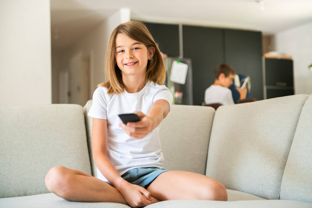 A girl holding remote control and watching TV show - Photo, Image