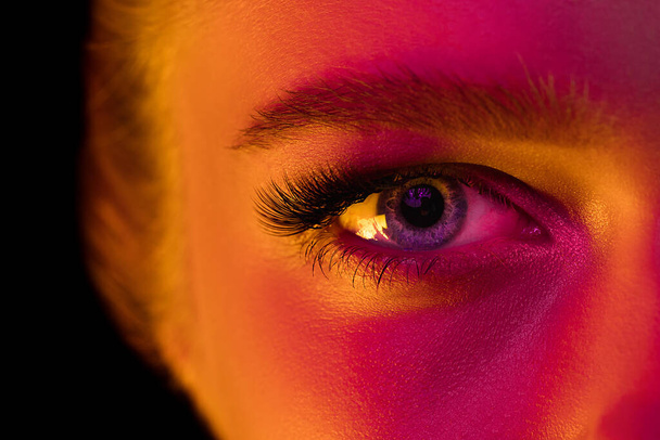 Close up portrait of female fashion model in neon light on dark studio background. - Фото, изображение