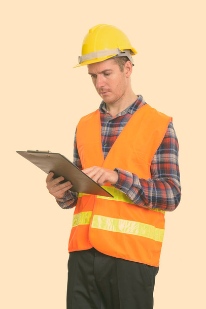 Studioaufnahme eines Bauarbeiters beim Lesen auf Klemmbrett - Foto, Bild