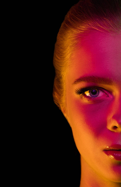 Portrait of female fashion model in neon light on dark studio background. - Photo, image