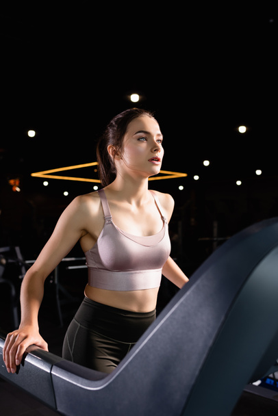 young sportswoman running on treadmill in sports center - Foto, imagen