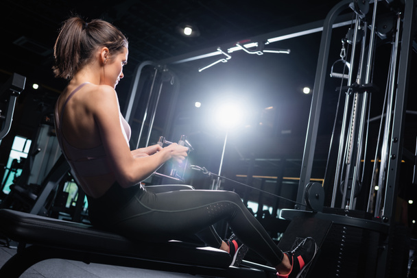 young sportswoman exercising on rowing machine in gym - Foto, Imagen