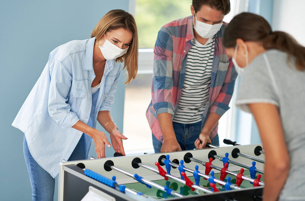 Couple of students wearing masks playing table soccer in the campus - Фото, изображение