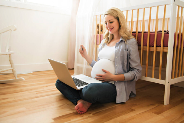Ελκυστική νεαρή έγκυος γυναίκα με φορητό υπολογιστή - Φωτογραφία, εικόνα
